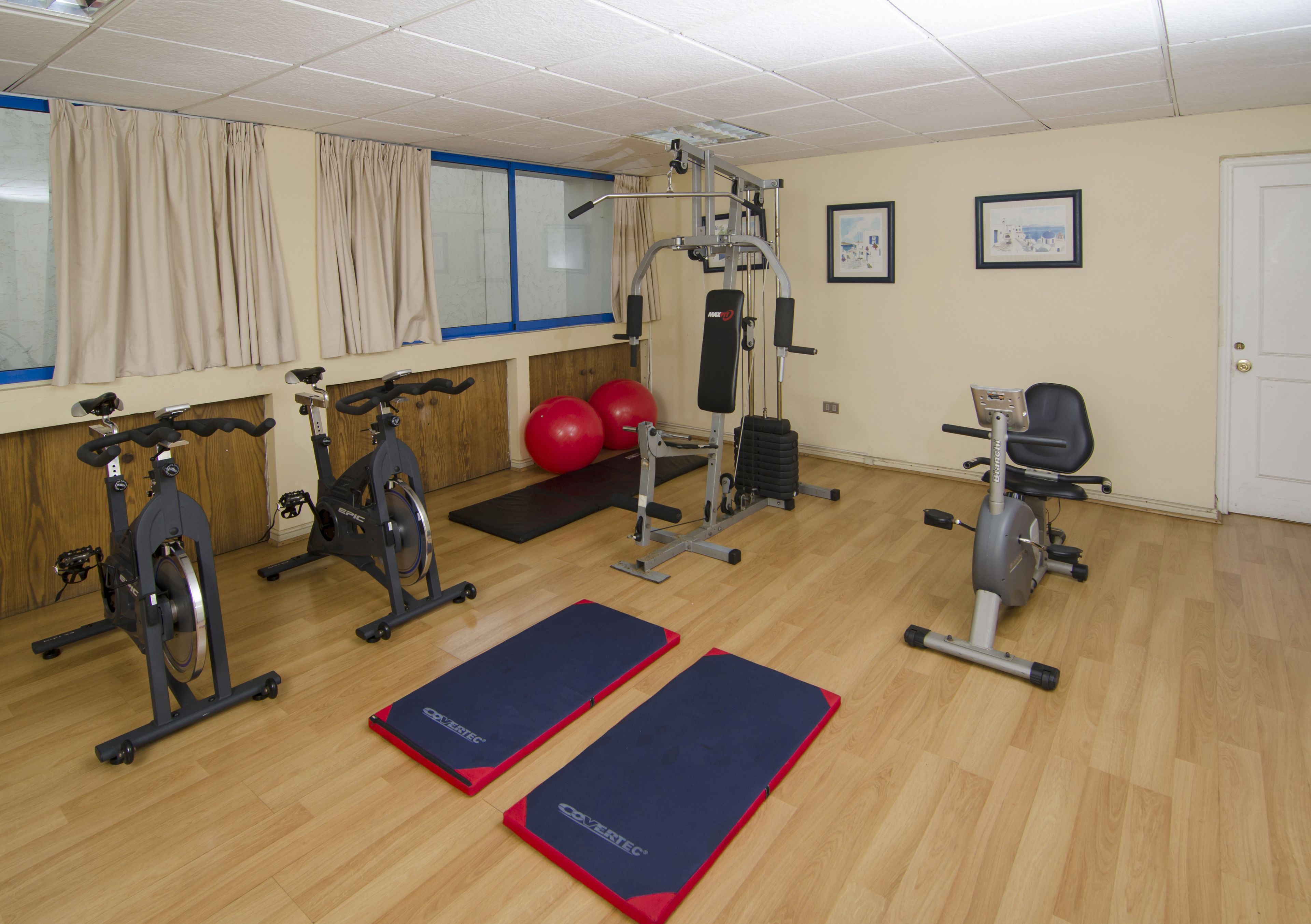 A gym with exercise equipment, mats, and a wall-mounted TV.