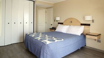 A hotel room with a bed, bedside tables, a wardrobe, and a door.