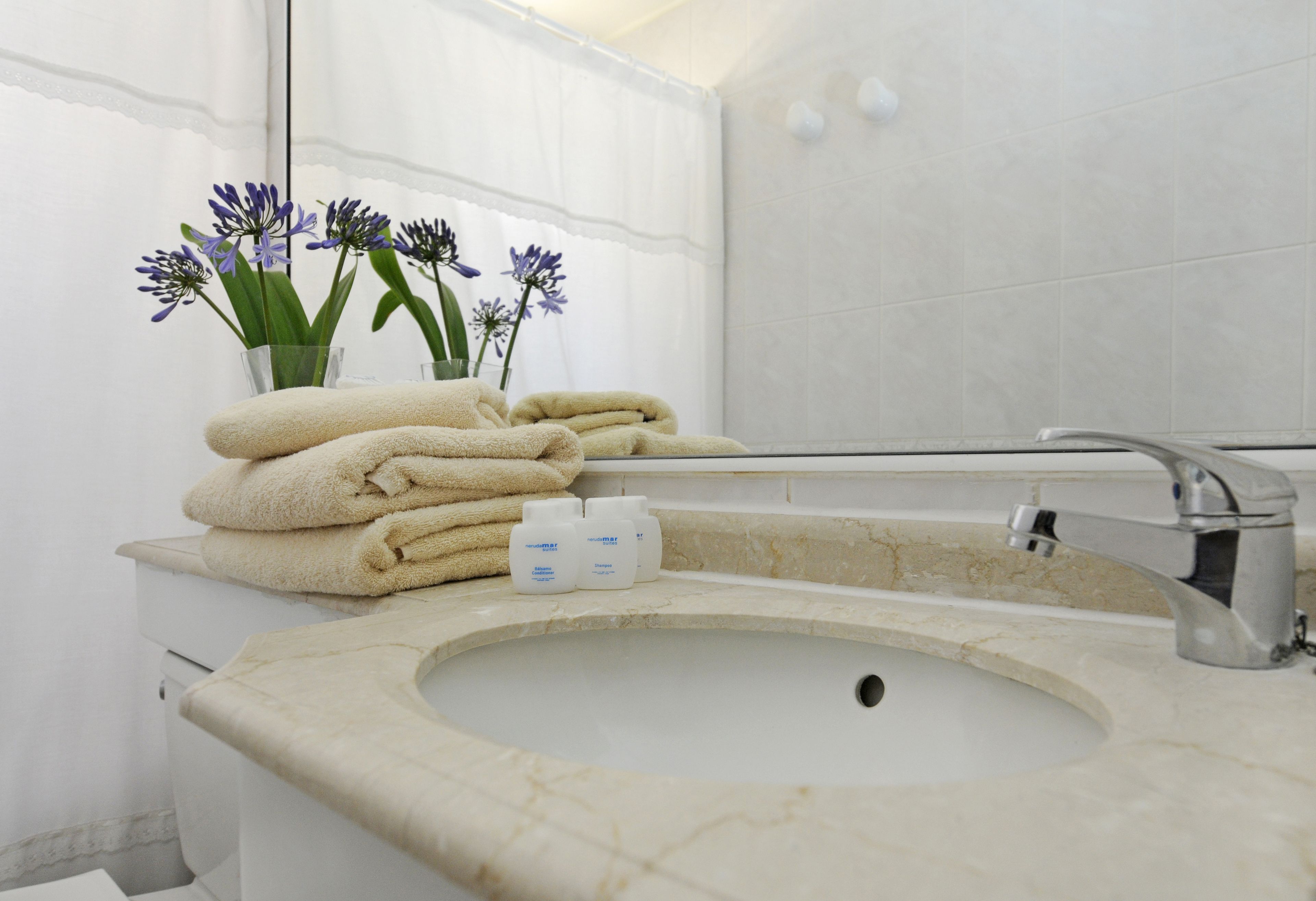 A bathroom with a sink, mirror, and towels.