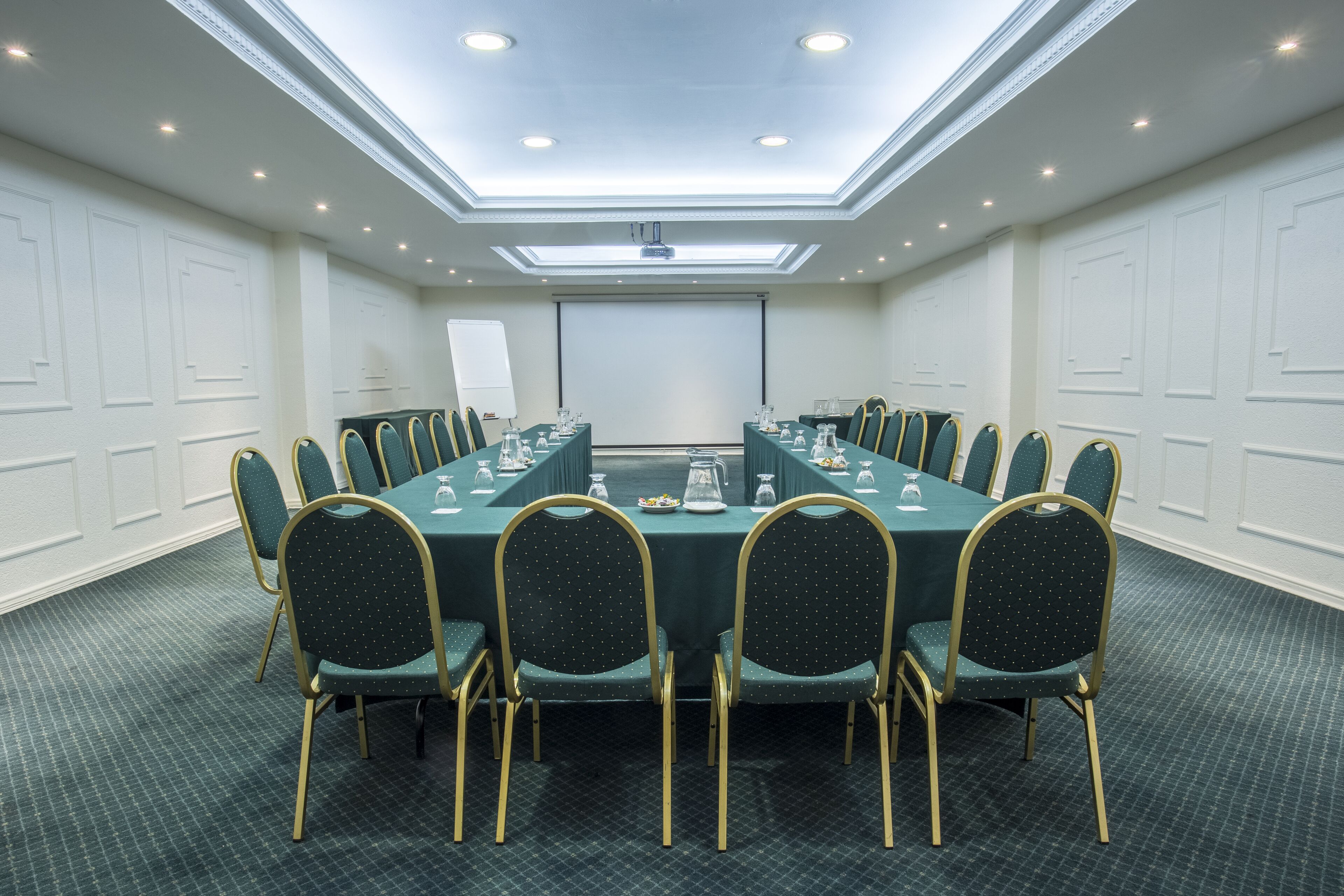 A conference room with a long table, chairs, a projector screen, and a whiteboard.