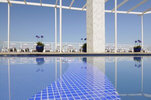 Una piscina al aire libre, sillones reclinables de piscina