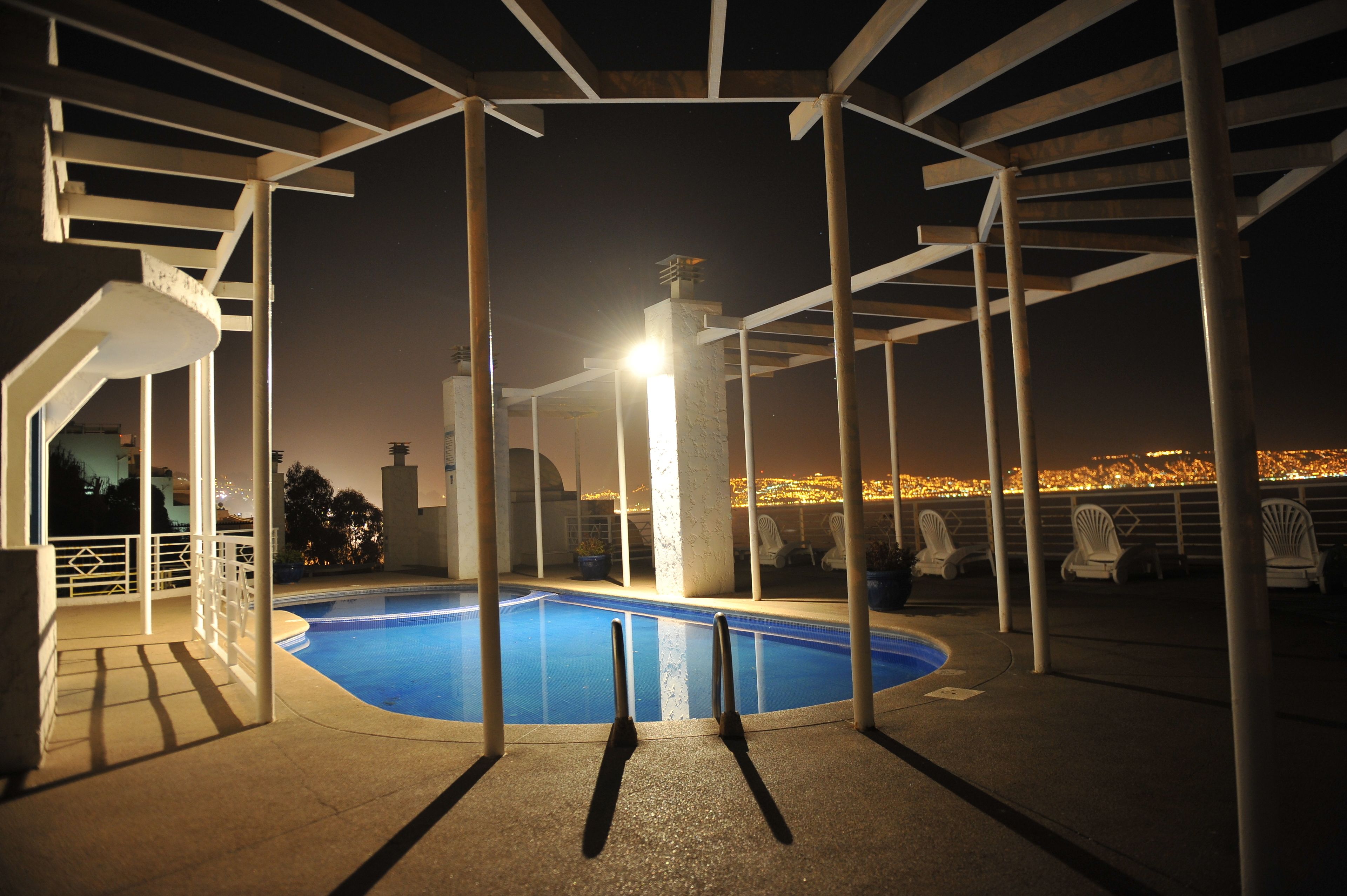 A nighttime swimming pool area with a view of a cityscape.