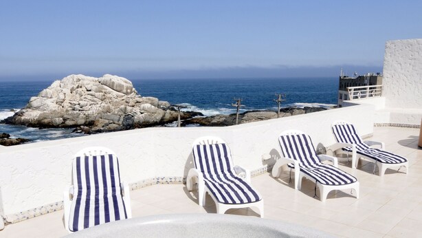 A hot tub with lounge chairs, a rocky outcrop, and a view of the ocean. - MR Mar Suites (Vina del Mar)