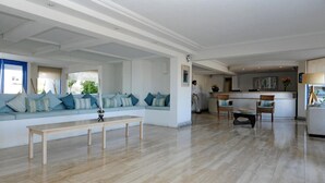 A spacious living area with a light-colored sofa set, a wooden coffee table, and a kitchen area in the background. - MR Mar Suites (Vina del Mar)