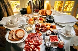 A breakfast buffet with various food items, including bread, pastries, and meats, arranged on a table. - Valdepalacios (Torrico)