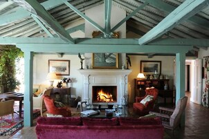 A cozy living room with a fireplace, comfortable seating, and a rustic ceiling.