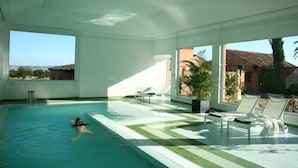 An indoor swimming pool with a view of the countryside, a water feature, and lounge chairs. - Valdepalacios (Torrico)