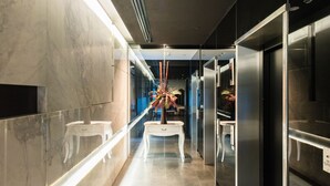 A modern hallway with marble walls, a glass partition, and a central decorative plant.