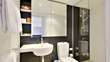 A modern bathroom with a white sink, toilet, and glass-enclosed shower.