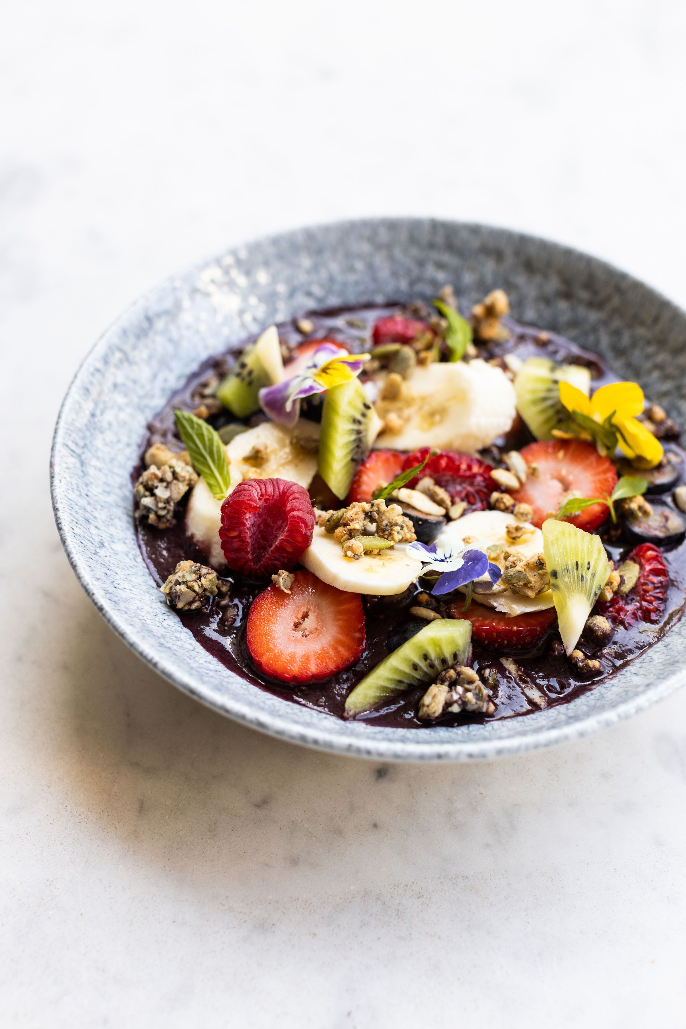 Un tazón de ensalada de frutas con diversas frutas y granola.