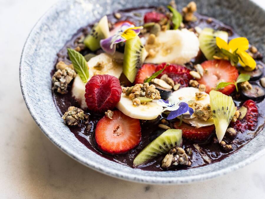 Un tazón de ensalada de frutas con diversas frutas y granola.