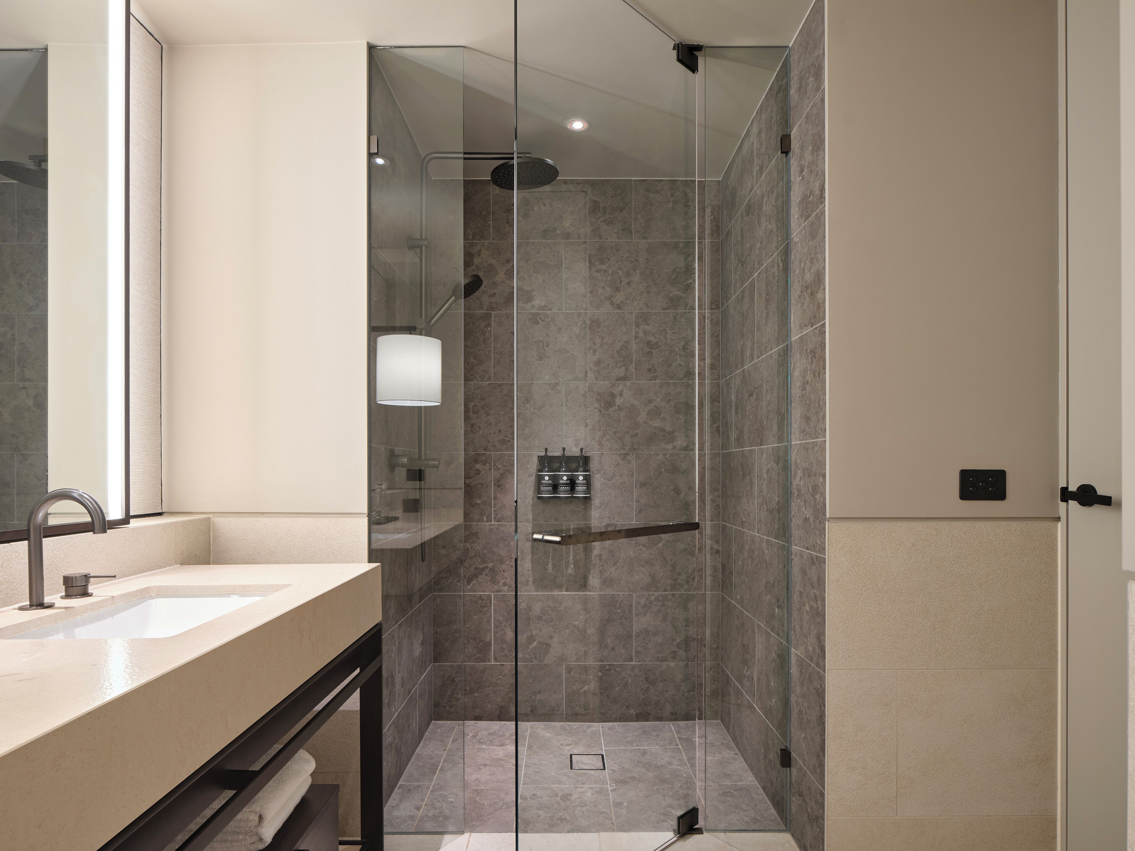A modern bathroom with a glass-enclosed shower, a sink, and a mirror.
