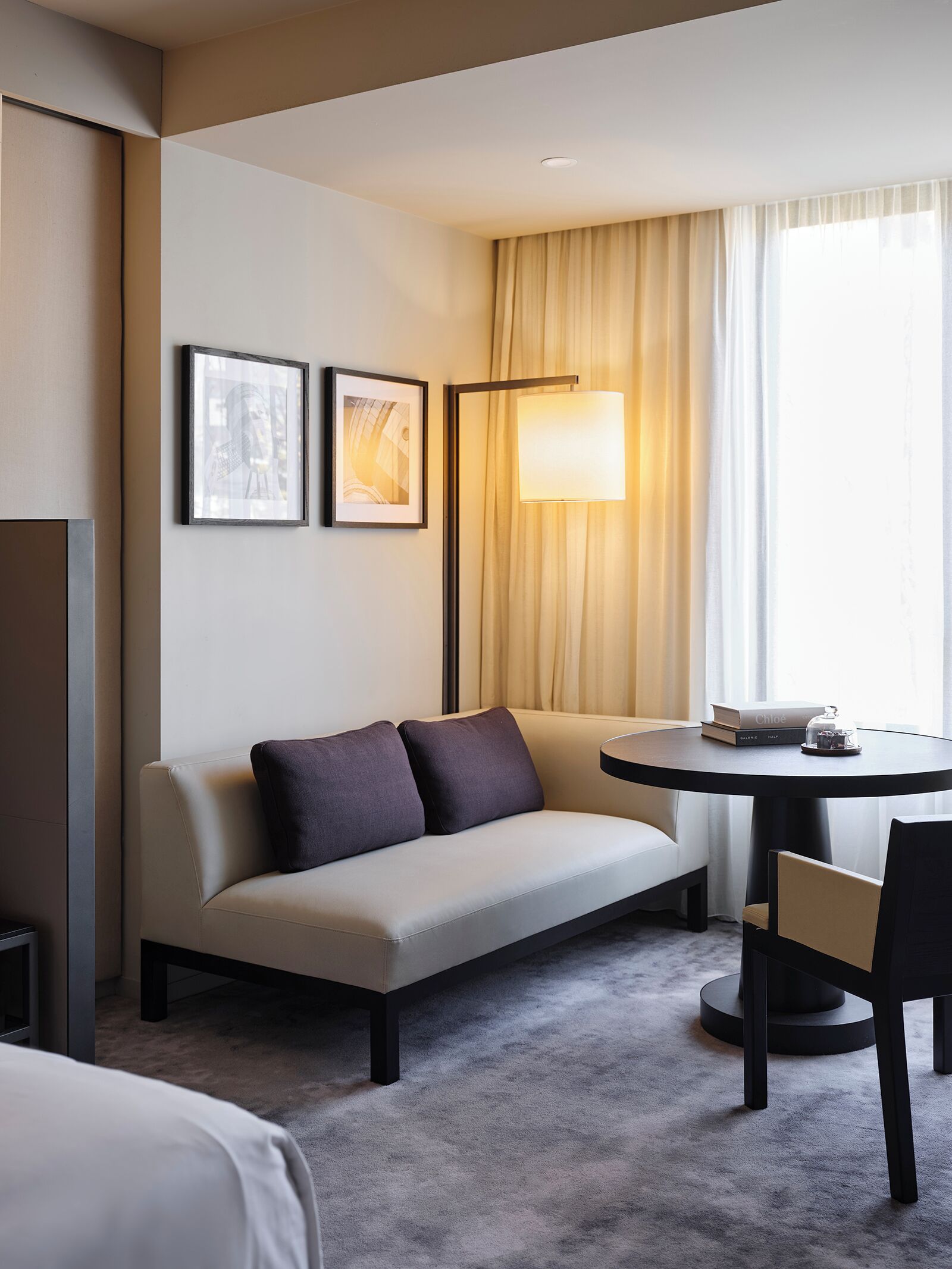 Ett hotellrum med en soffa, ett runt bord och en lampa.