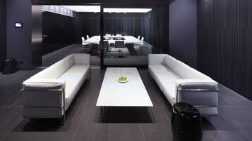 Une salle de conférence moderne, dotée d’une longue table, de canapés blancs et d’une poubelle noire.