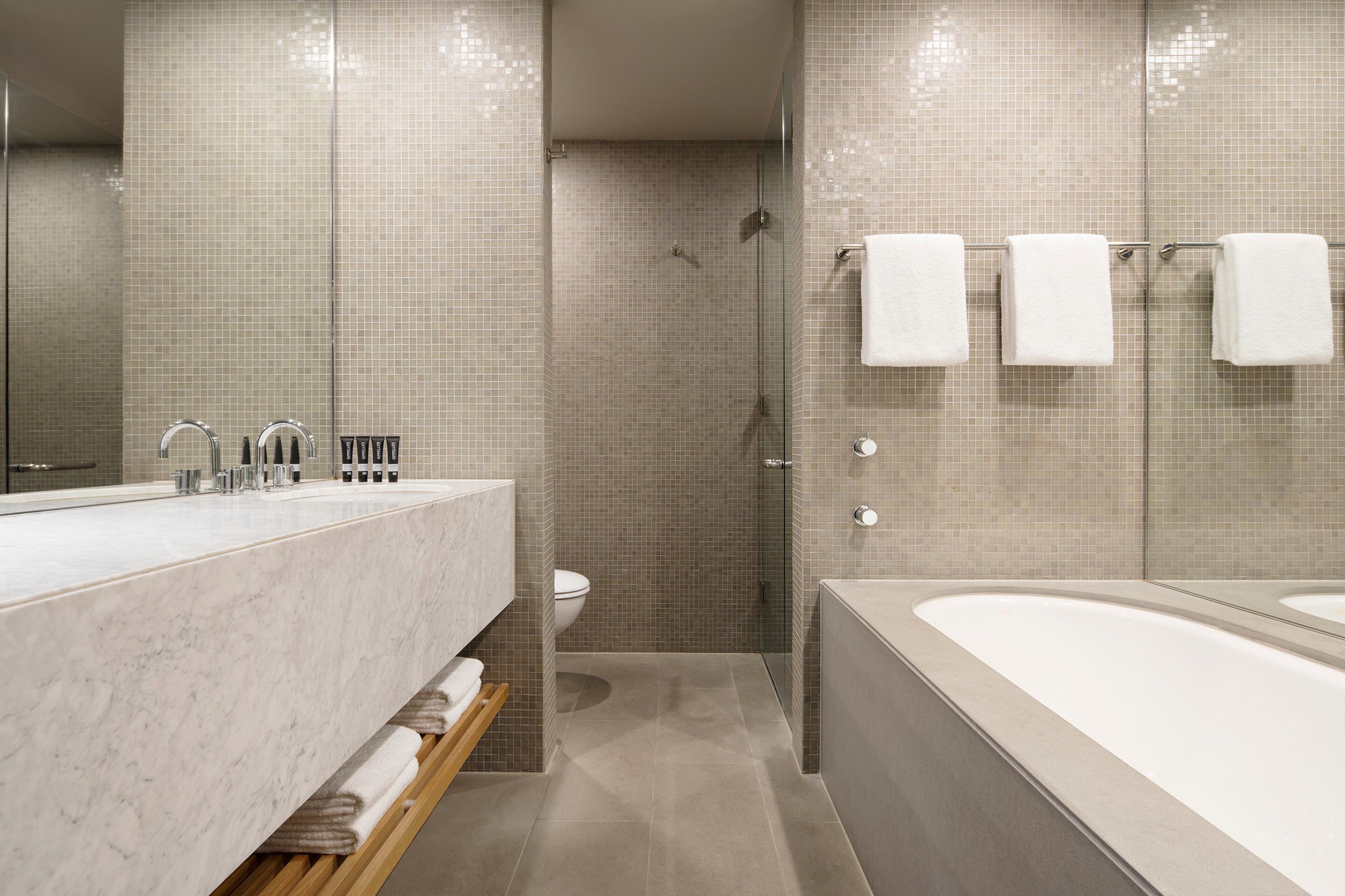 A modern bathroom with a marble sink, a bathtub, and a shower area.