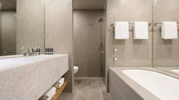 A modern bathroom with a marble sink, a bathtub, and a shower area.