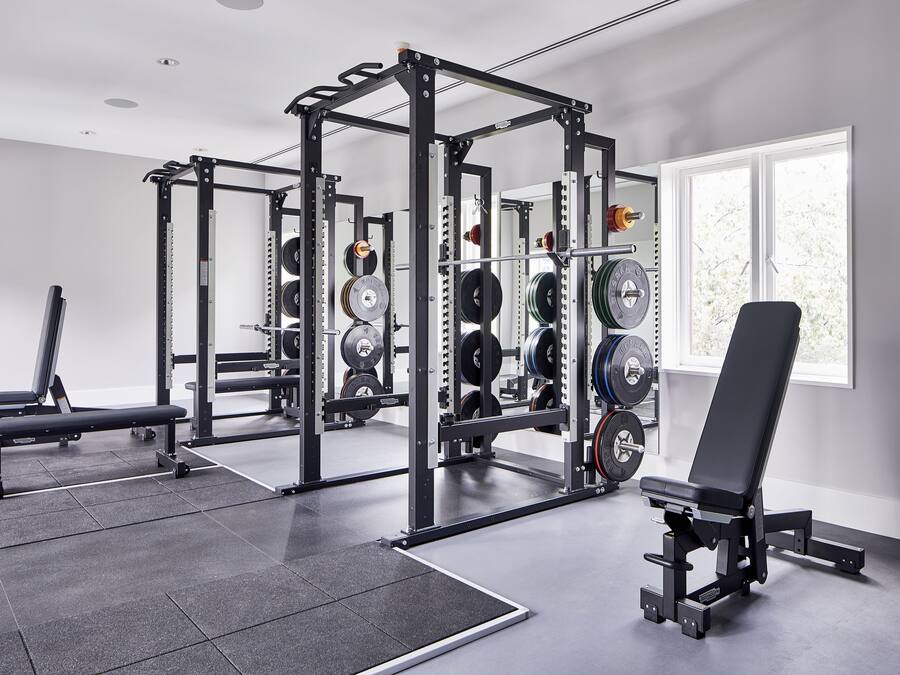 A gym with weightlifting equipment, a bench, and a window with natural light.