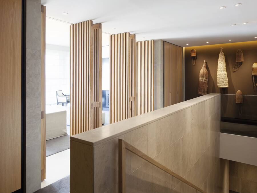 A modern hotel lobby with a wooden reception desk, vertical wooden slats, and a display of woven baskets.