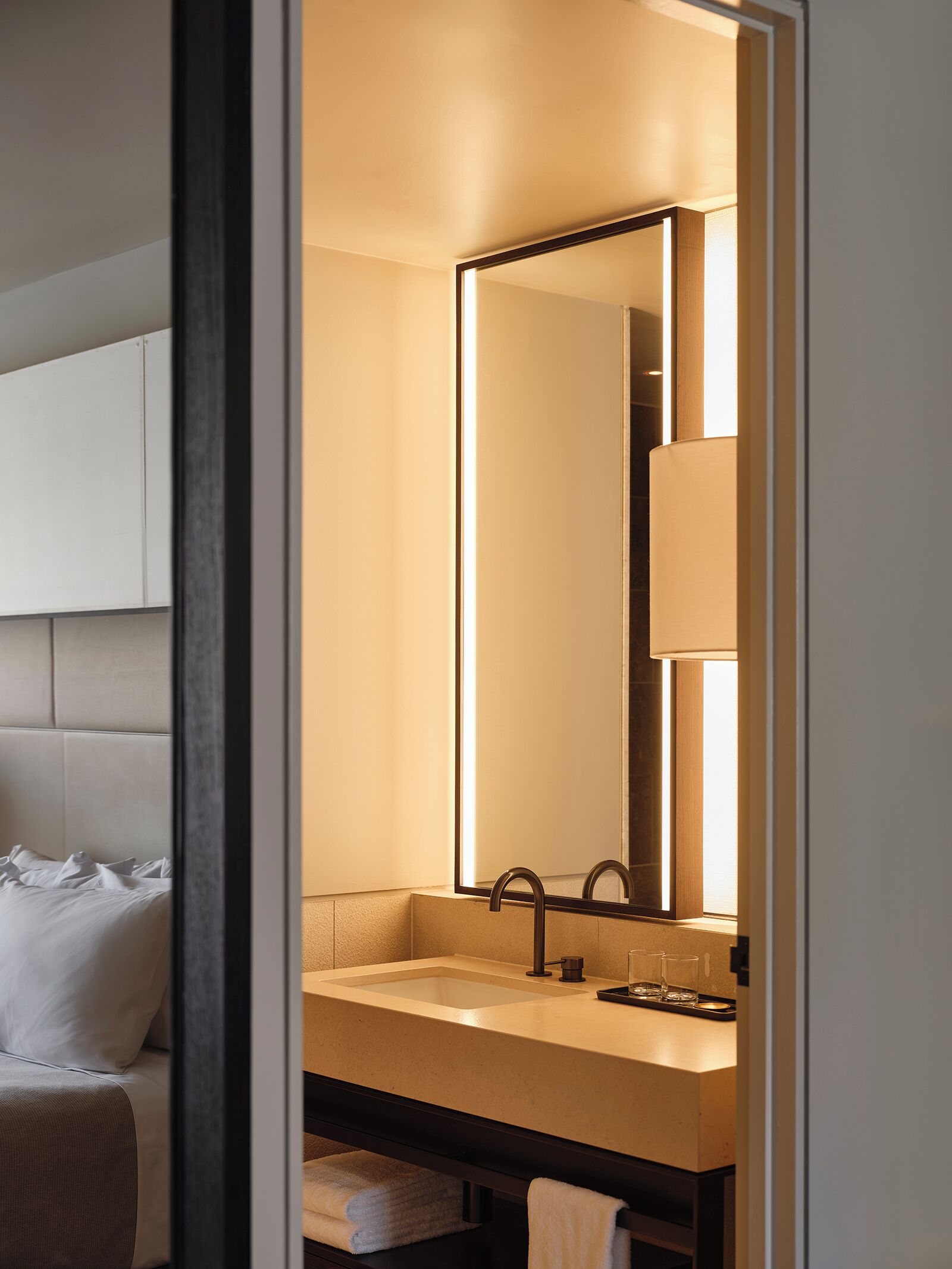 Un baño moderno con un espejo grande, un lavabo y un inodoro.