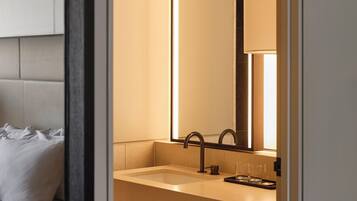 Un baño moderno con un espejo grande, un lavabo y un inodoro.