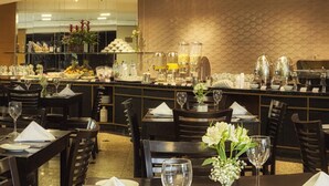 Un restaurante con mesas de madera oscura, servilletas blancas y cristalería transparente.