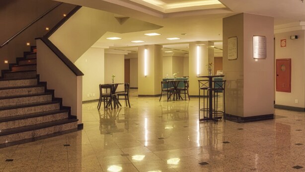 Un hall amplio con suelo de mármol, una escalera y varias mesas y sillas.