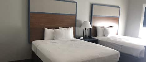 Ein Hotelzimmer mit zwei Betten, einem Nachttisch mit Lampe und einem Fenster.