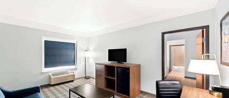 Habitación de hotel con un ventanal grande, televisor de pantalla plana, escritorio con lámpara, sofá y una silla.