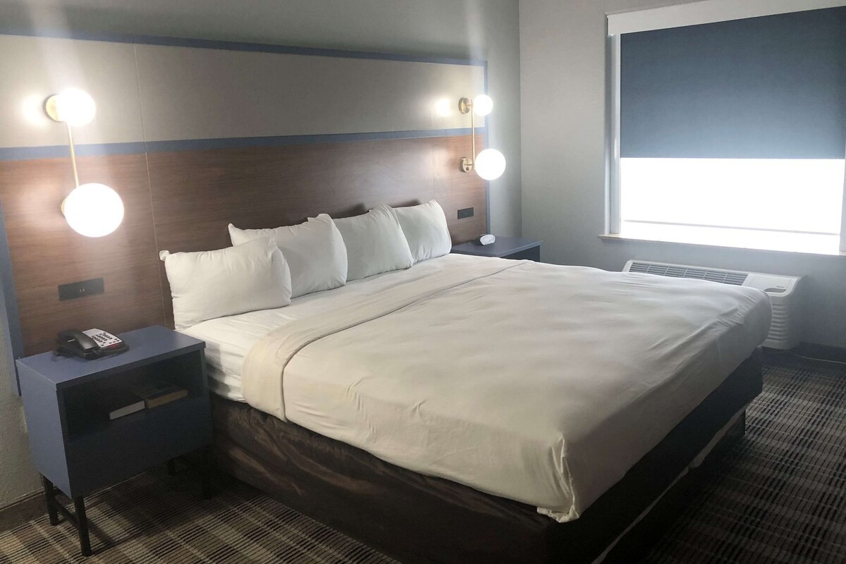 A hotel room with a bed, bedside tables, a telephone, and wall-mounted lights.