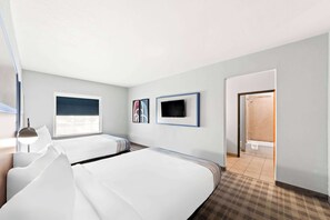 A hotel room with two beds, a TV, and a bathroom visible through an open door.