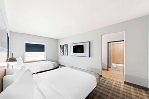 Ein Hotelzimmer mit zwei Betten, einem Fernseher und einem durchgegangenen Tür sichtbaren Badezimmer.