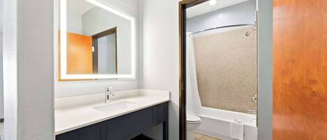 A modern bathroom with a white sink, dark vanity, and a separate shower area.