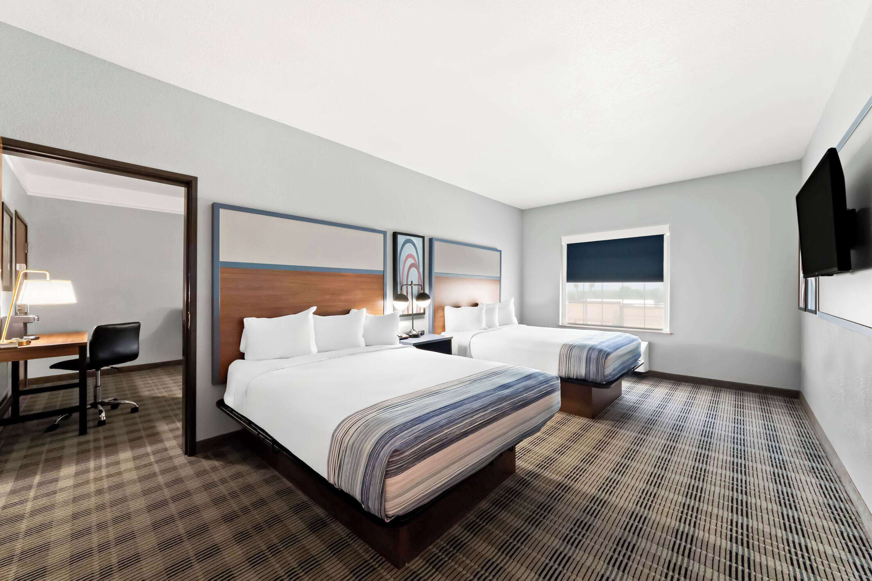 A hotel room with a large bed, a desk, a chair, and a TV.
