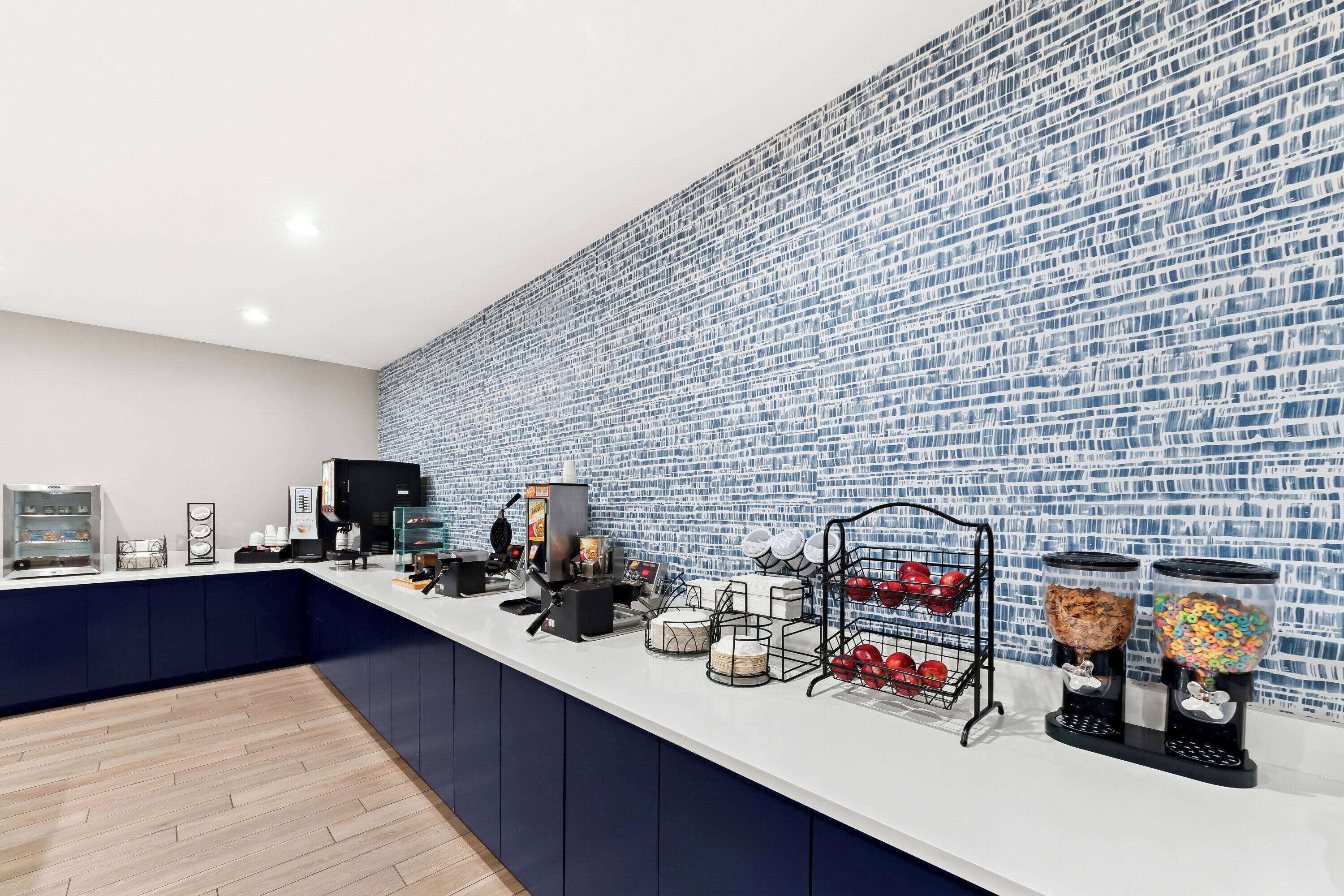 A modern kitchen area with a white countertop, blue cabinets, and a patterned backsplash.