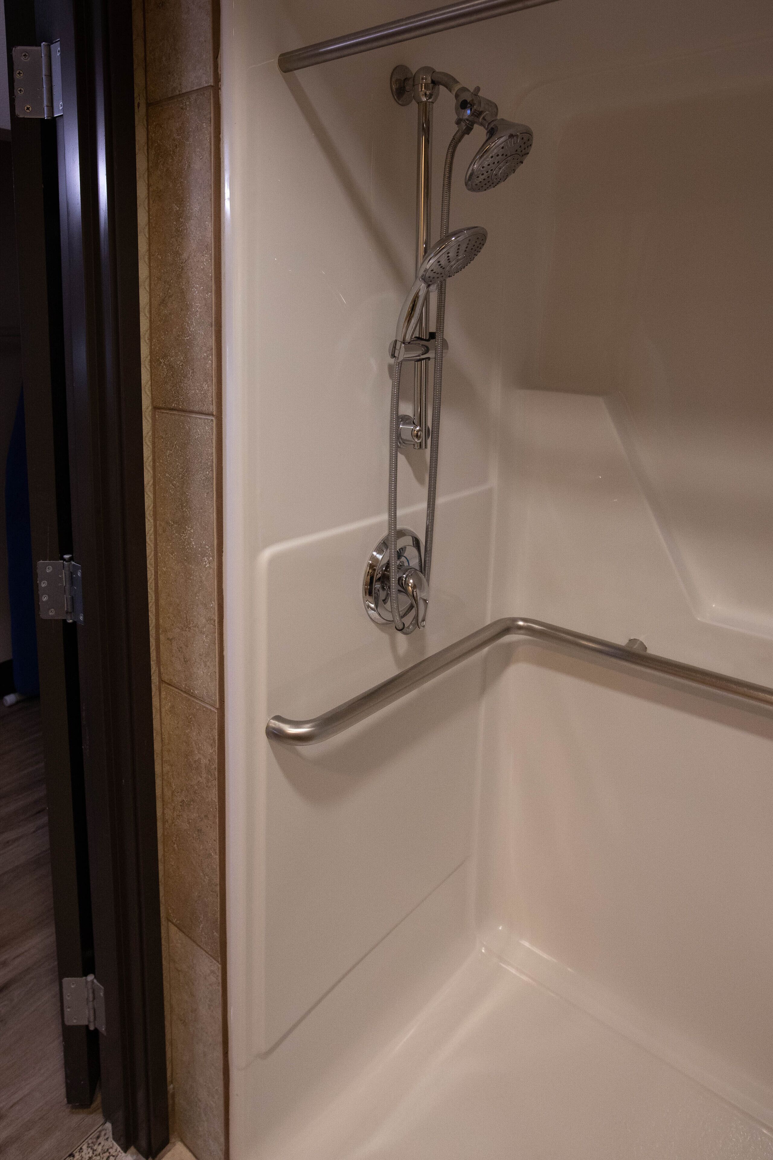 Ducha moderna con cabezal de ducha de mano y otro fijo, barra de seguridad y grifo de cromo.