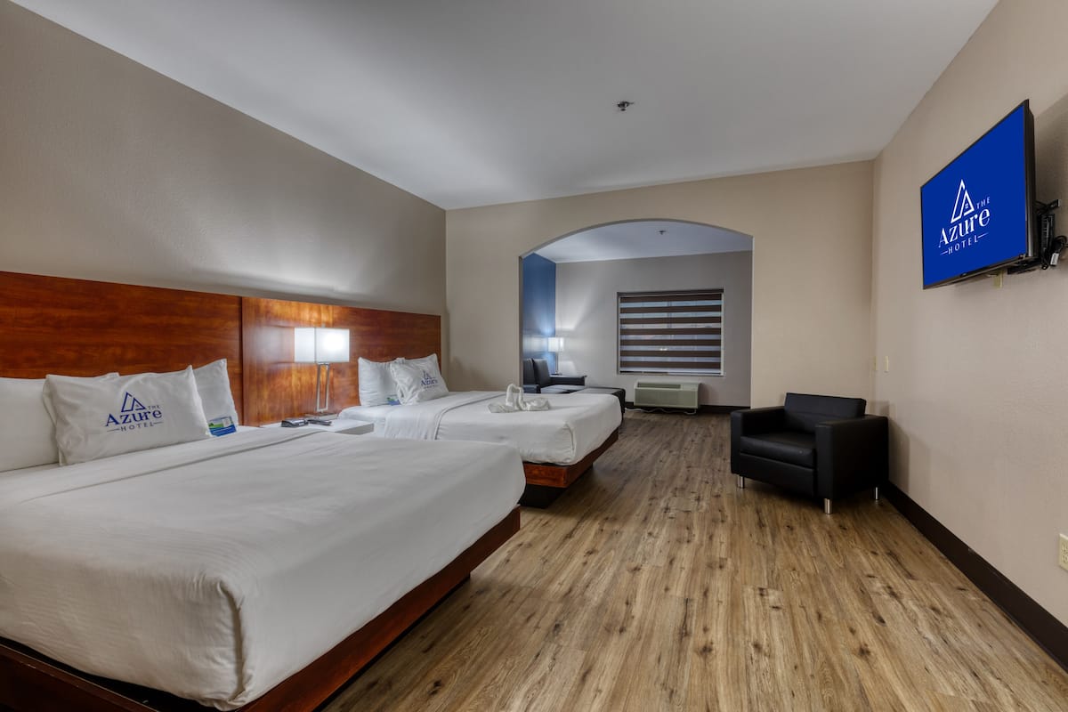 Une chambre d’hôtel avec deux lits, une télévision, un bureau et une chaise.