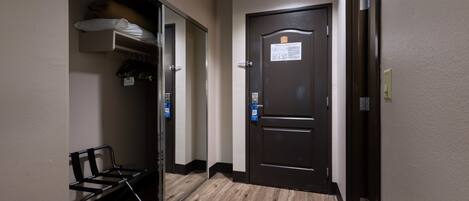 A hotel hallway with a bench, a coat closet, and a door with a sign.