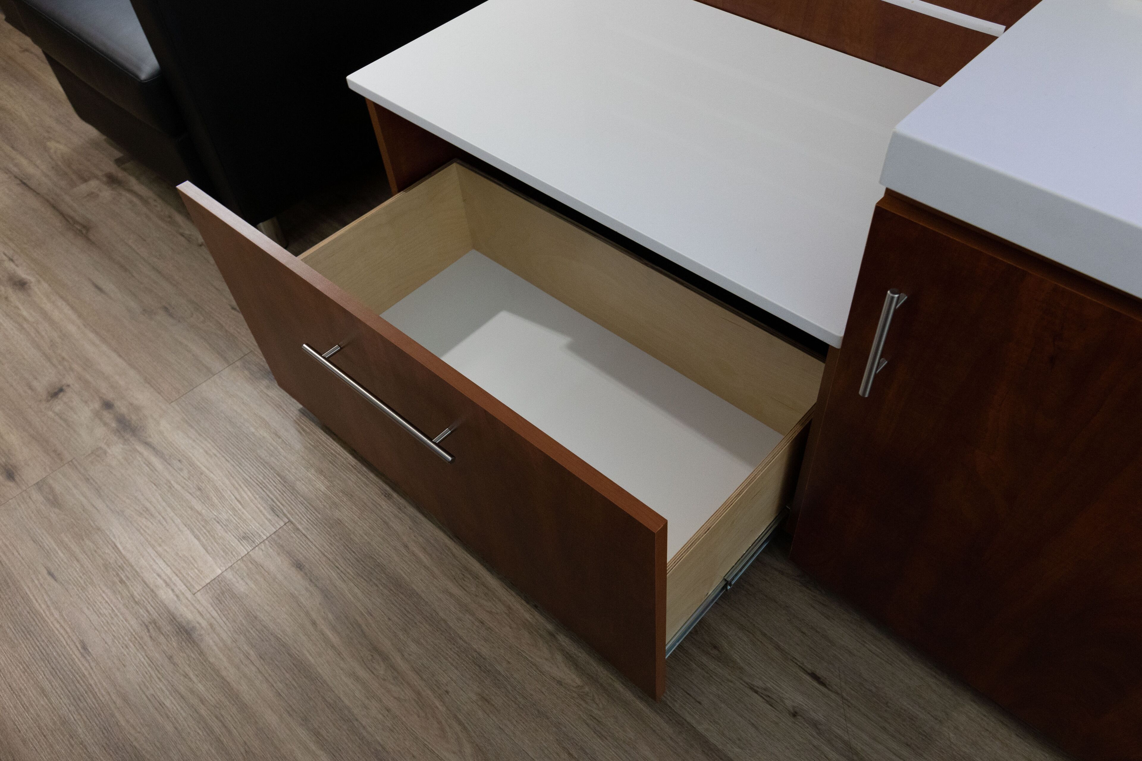 Un mueble de madera con encimera blanca y un cajón.