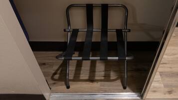 Une chaise en métal dotée d’un dossier et d’une assise à lattes, placée dans une pièce au plancher en bois et aux murs unis.
