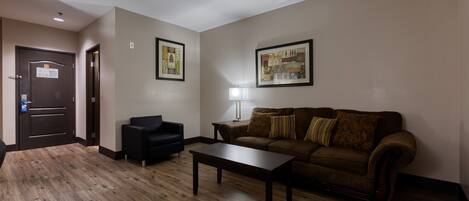 A living room with a brown sofa, a black armchair, a wooden coffee table, and two framed pictures on the wall.