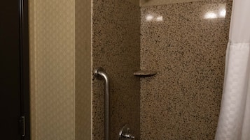 Un baño con bañera, ducha con barra de apoyo y una puerta.