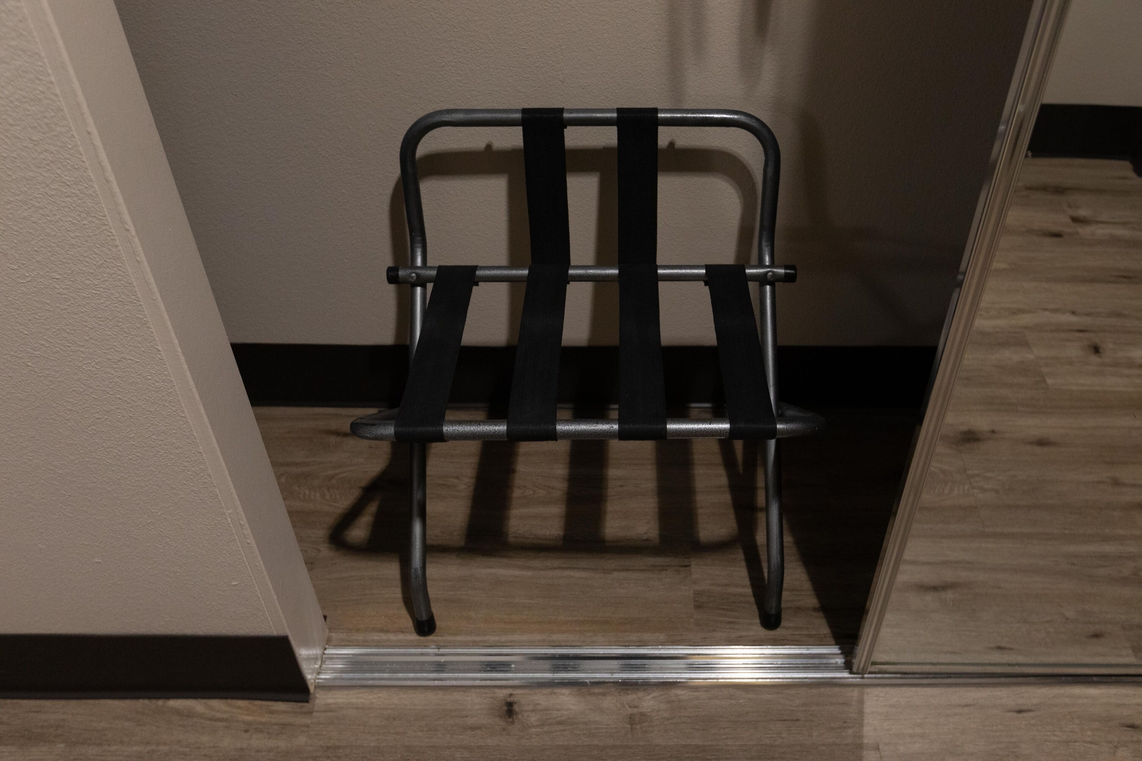A metal chair with a backrest and seat slats against a wall.