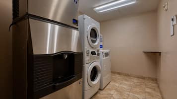 Un lavadero con refrigerador de acero inoxidable, lavadora y secadora.