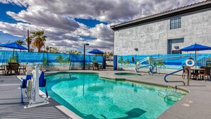 A swimming pool with a lifeguard chair, lounge chairs, and umbrellas.