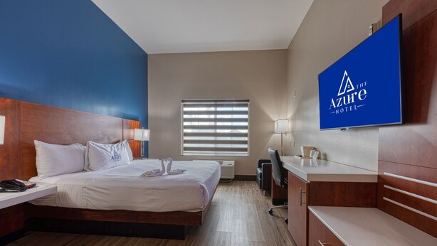 A hotel room with a bed, desk, and a TV displaying the Azure Hotel logo.