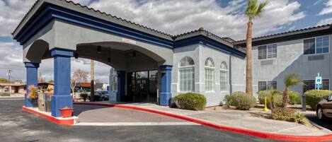 A building with a covered entrance, a clear sky, and a palm tree.