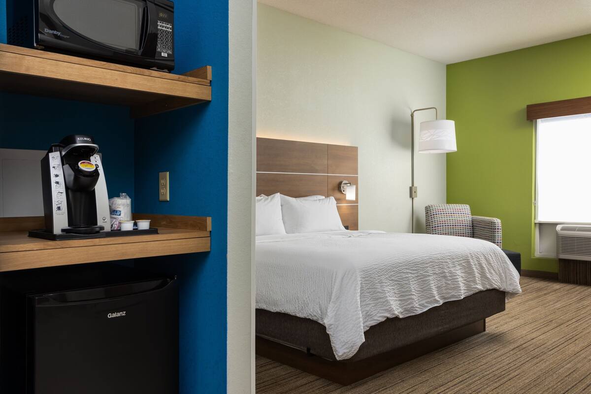 Ein Hotelzimmer mit Bett, einer Kaffeemaschine, einer Mikrowelle und einem kleinen Kühlschrank.