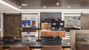 A modern coffee shop with a black table, wooden chairs, a sofa, and a coffee machine. - Holiday Inn Express & Suites Carrollton by IHG (Carrollton)
