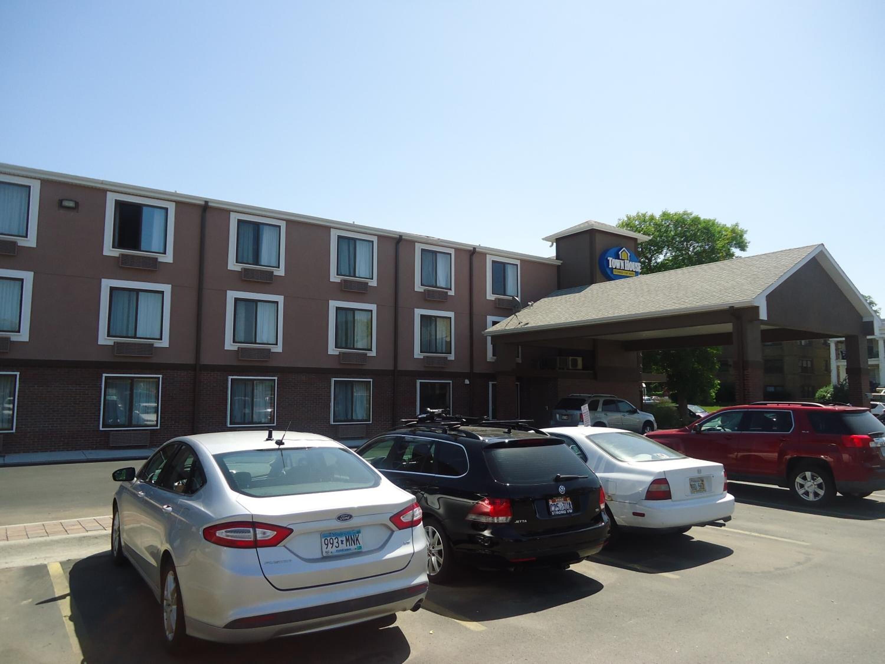 A parking lot with several cars parked in front of a building with a TownHouse sign.