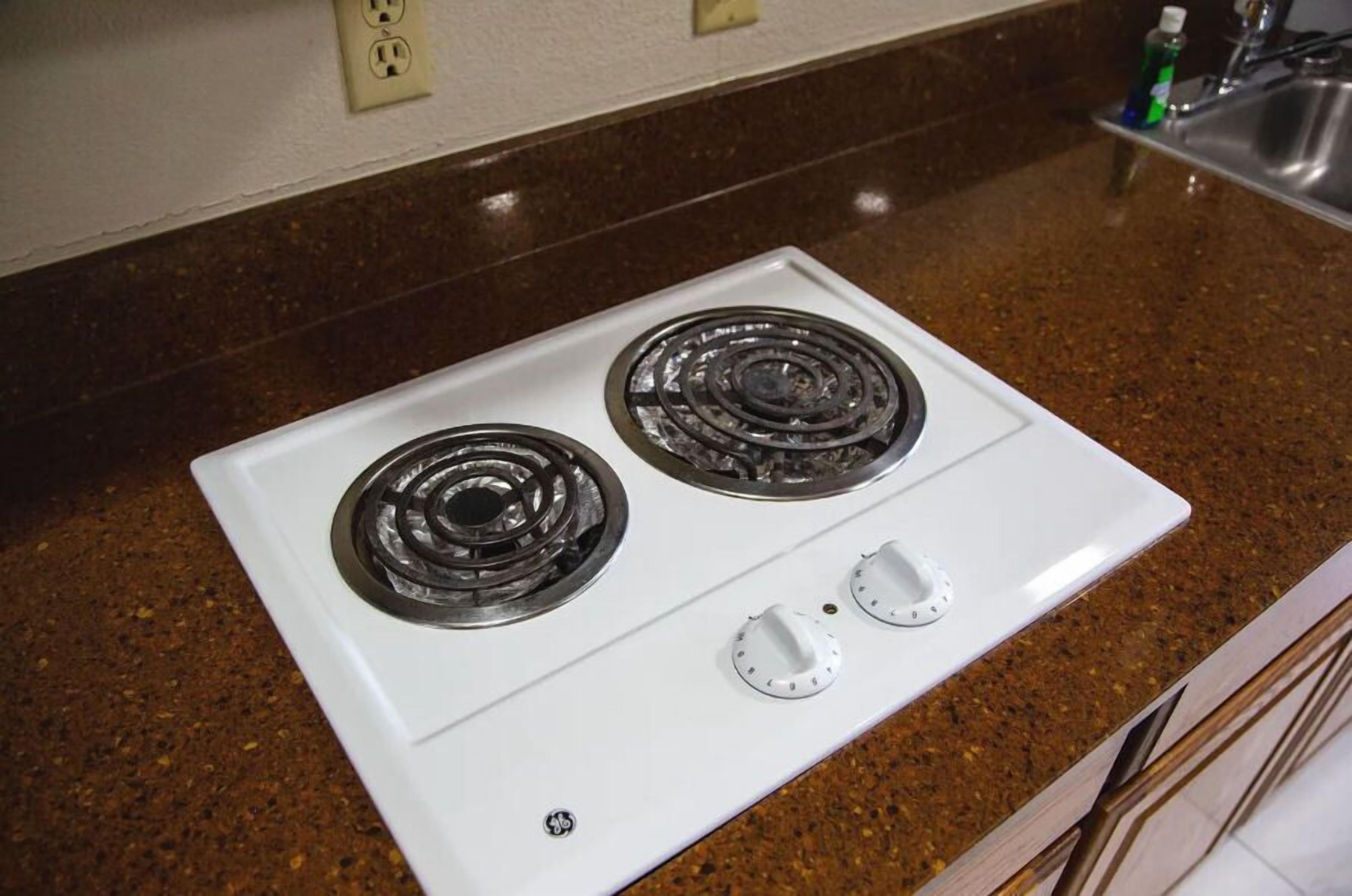 A white stove with two burners and two knobs on a granite countertop.